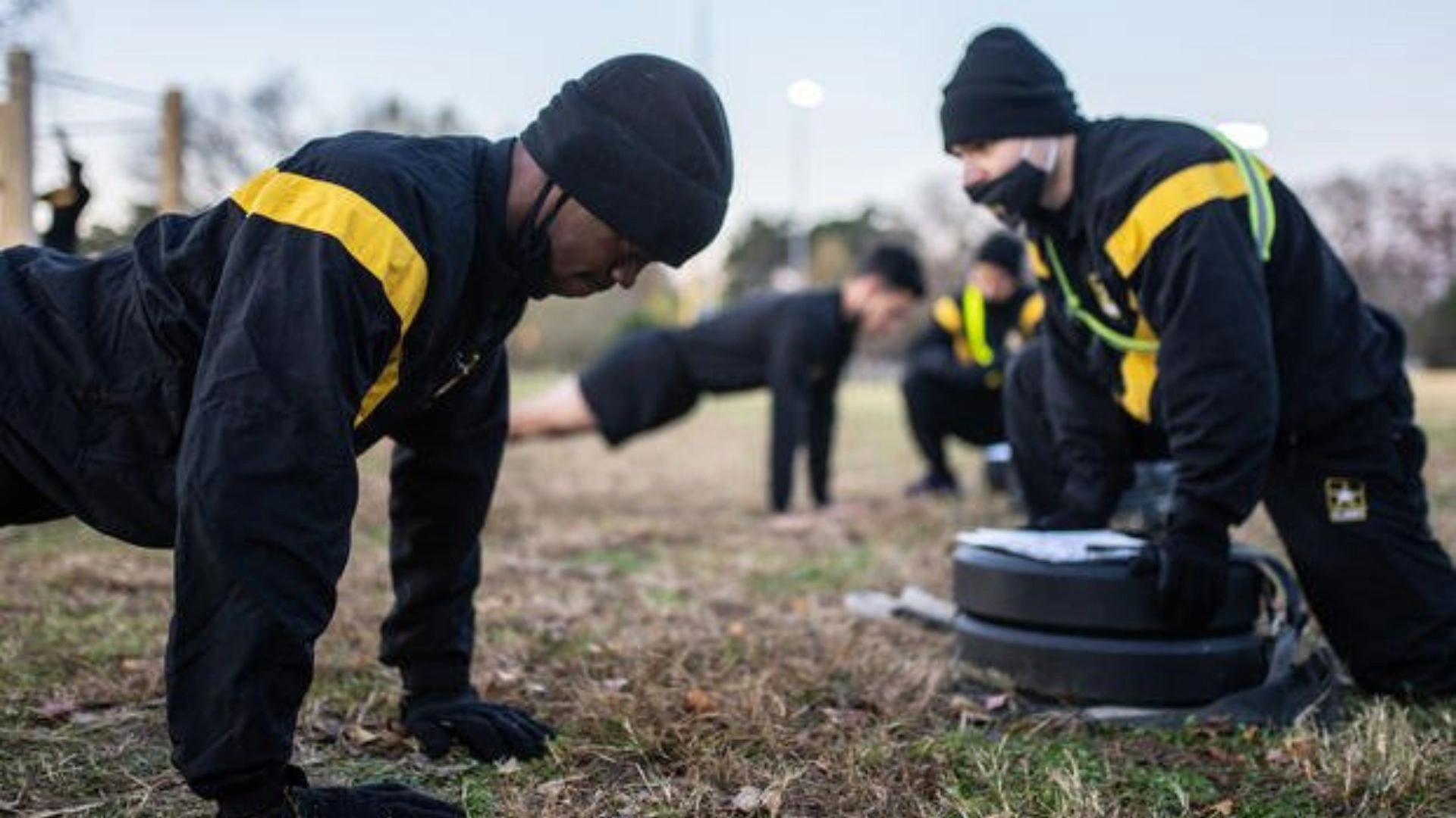 ACFT Calculator | Calculate Your Army Combat Fitness Test Score 5 Soldiers in black and yellow outfits doing push-up and kneeling by weights on a grassy field.