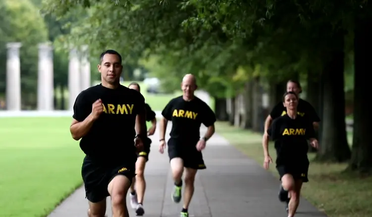 Soldiers in black "ARMY" shirts running the Two-Mile Run on a tree-lined path with grass on both sides